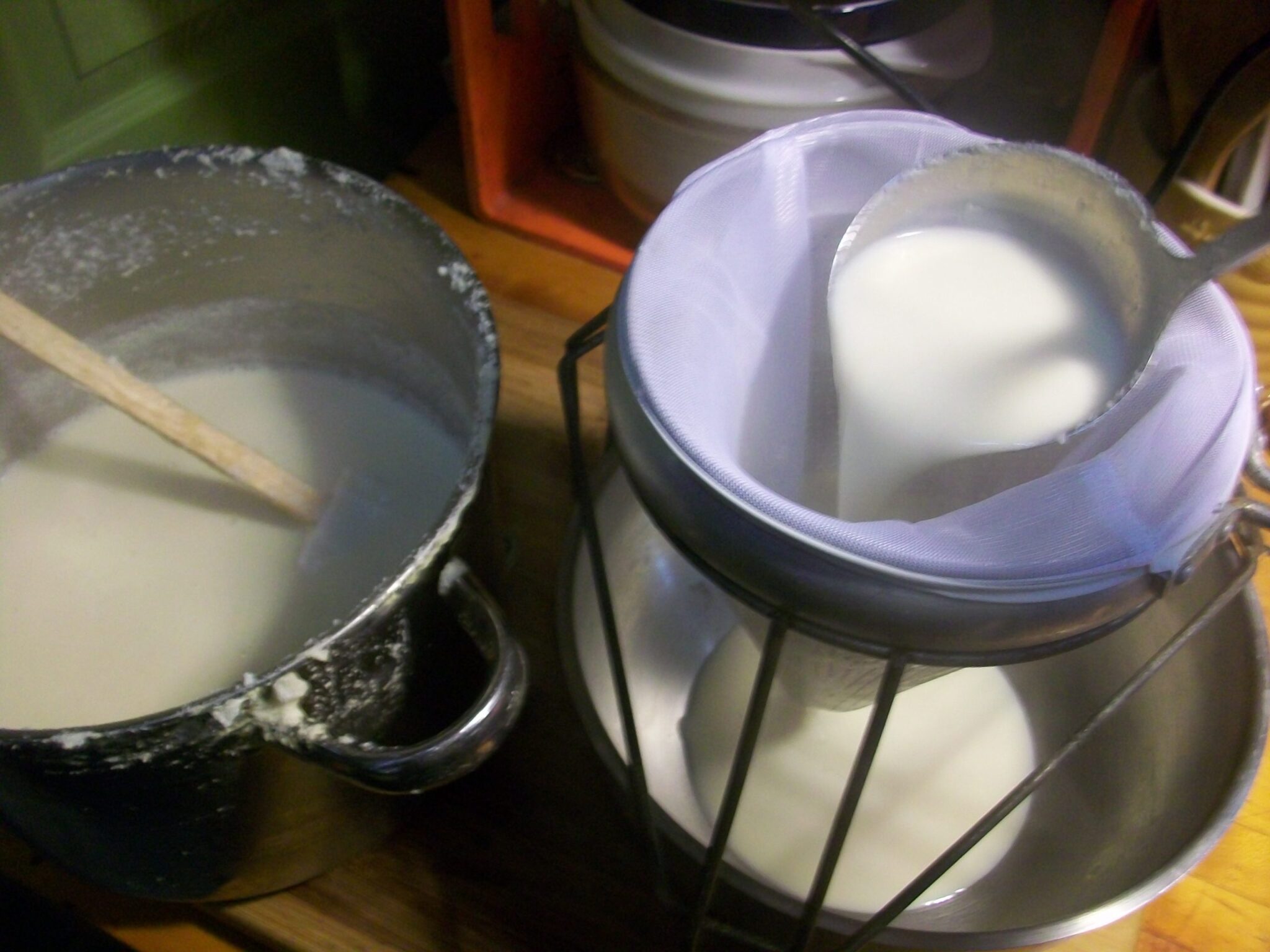 ladling homemade soymilk through a strainer to remove the soybean solids before making tofu with the soymilk