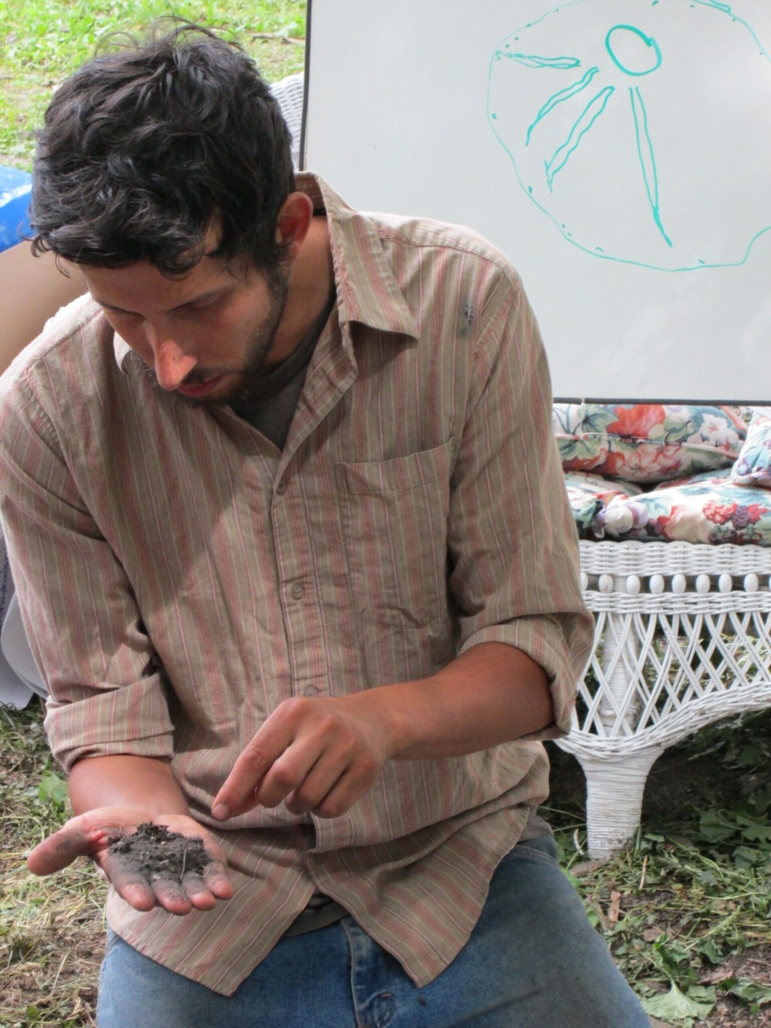 A man holds a palmful of soil and is examining it.