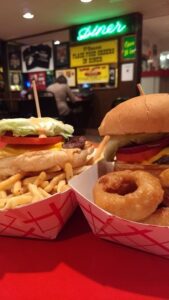 two paper baskets with giant pub burgers, fries, and onion rings 