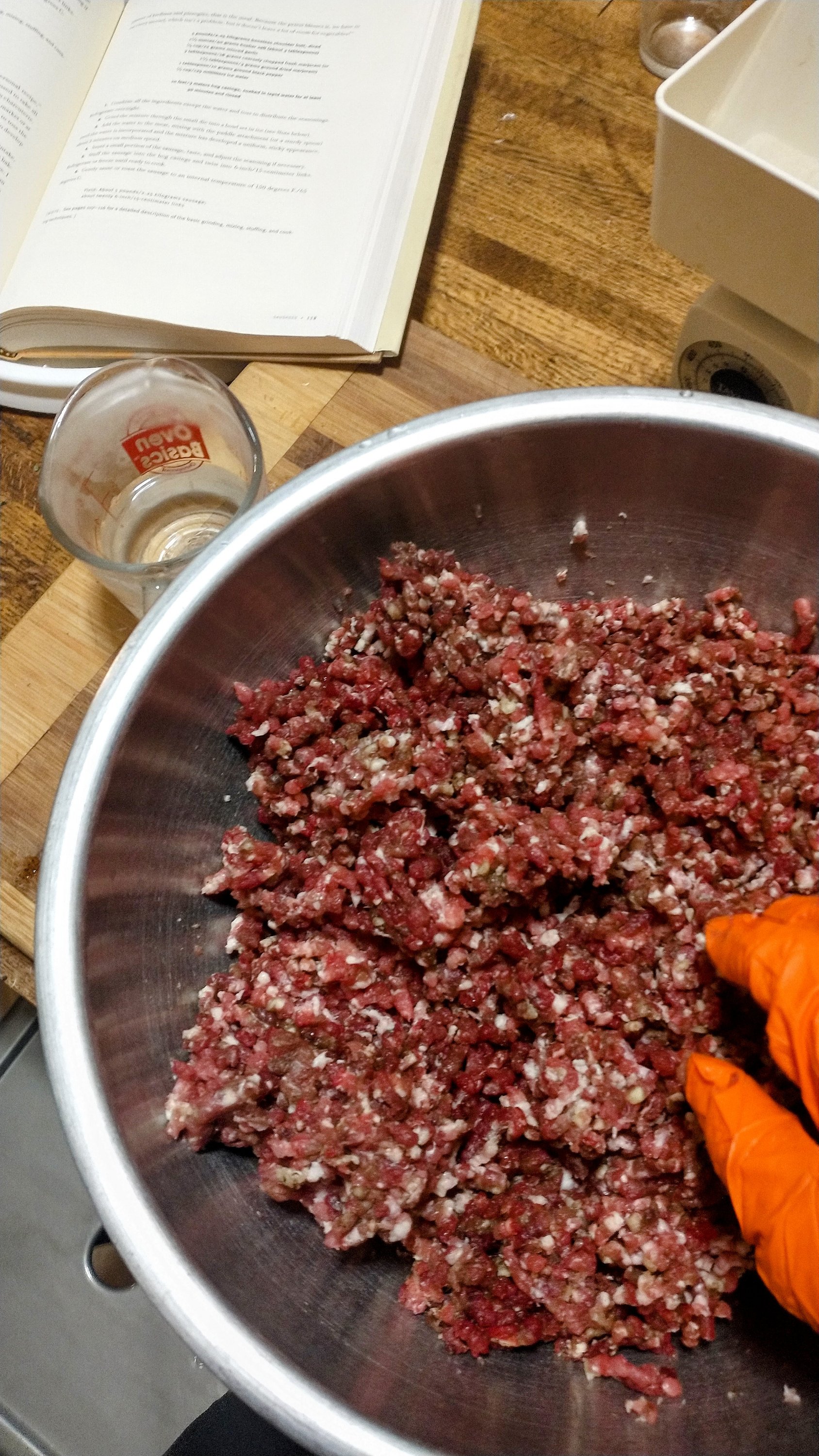 a bowl of ground meat and seasonings being mixed to make sausage.