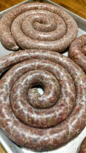 coils of homemade venison wiejeska sausage on a sheet pan.