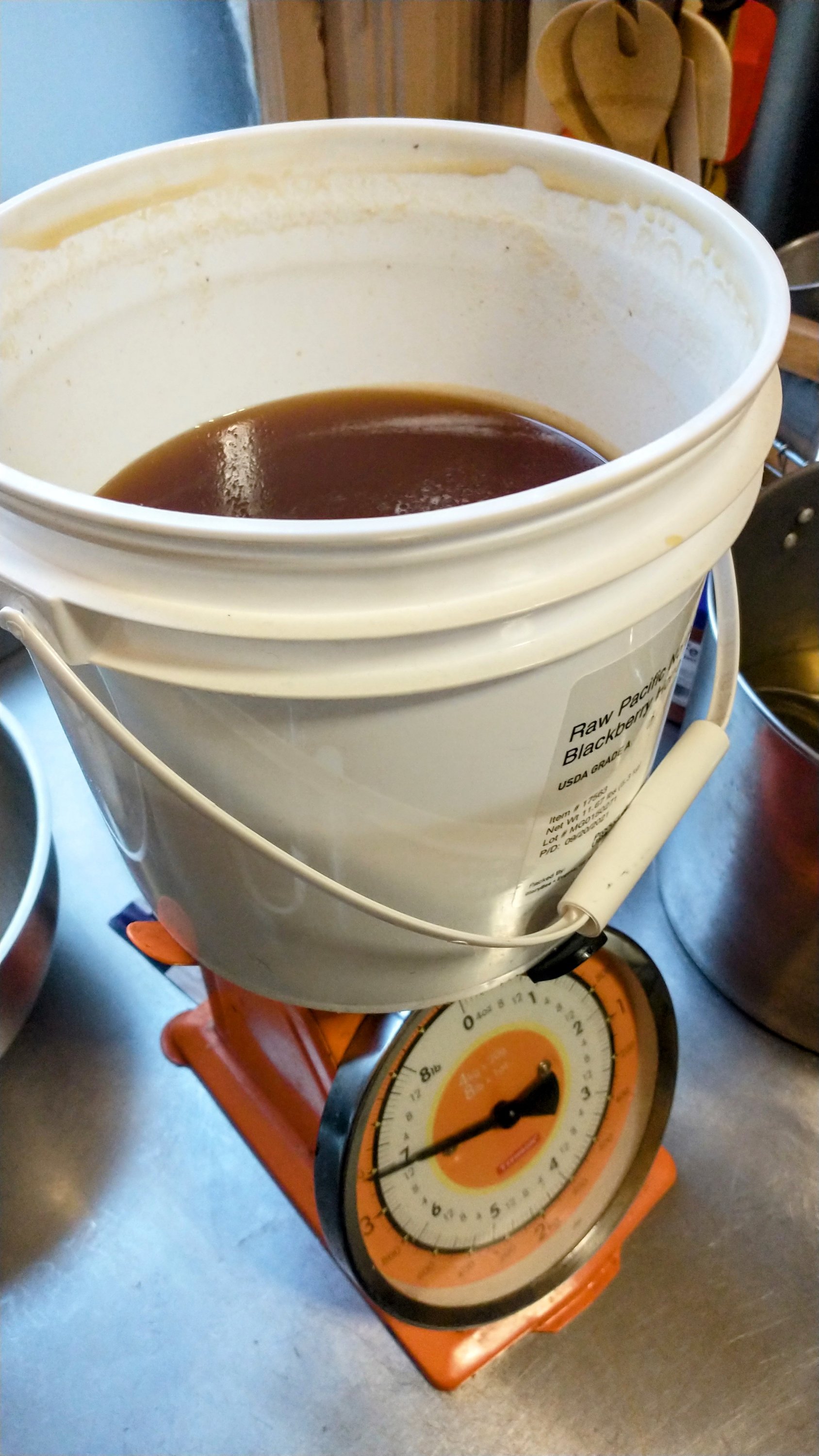 weighing a small bucket of honey on a bright orange kitchen scale