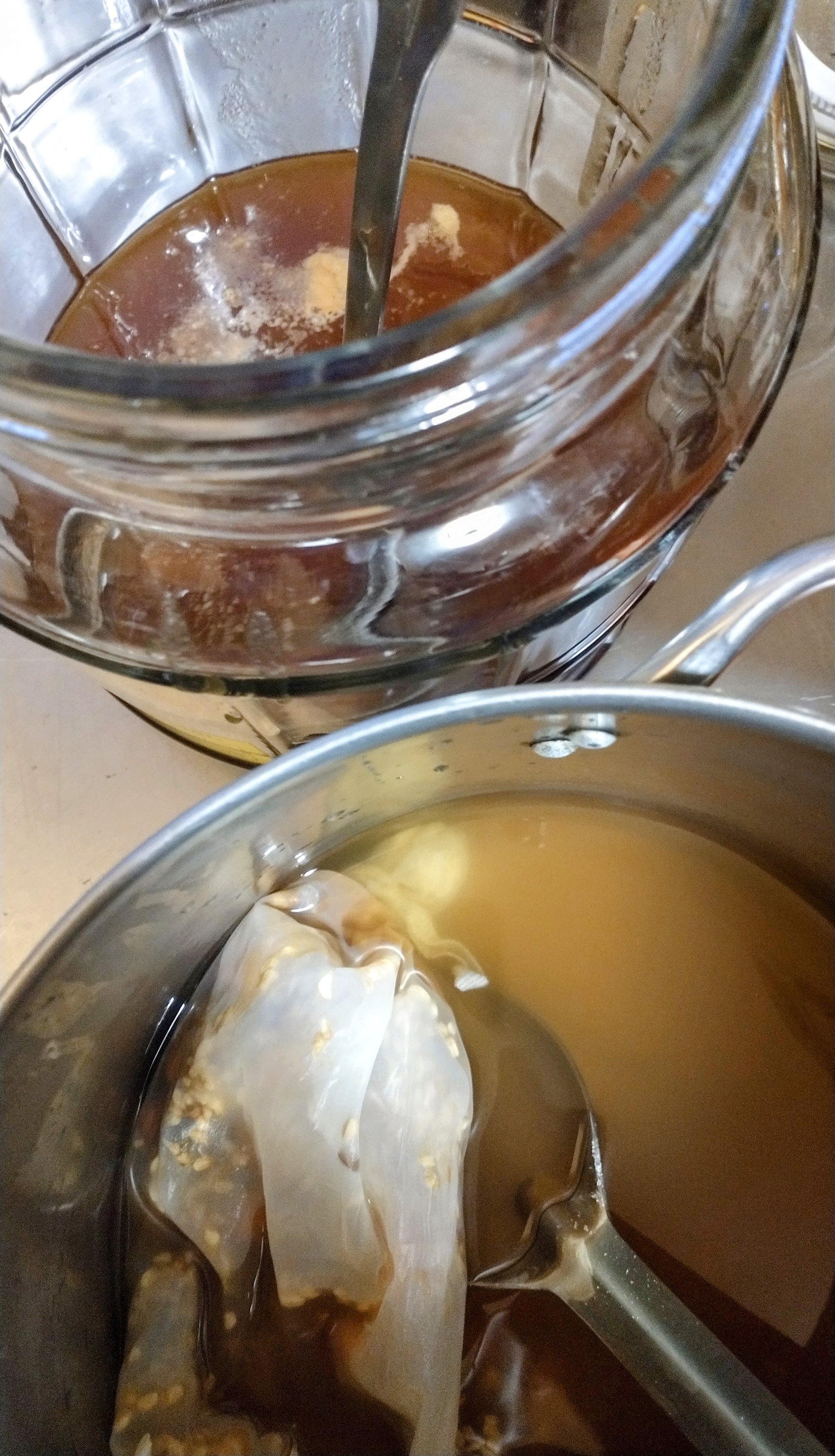 a one gallon glass fermenation jar and the nylon bag with the steeped rose hips and liquid about to be combined in the jar