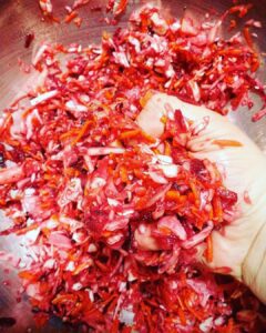 massaging shredded carrot, cabbage, and beet with salt and seasonings to make lactofermented sauerkraut kraut