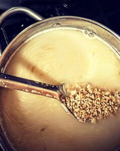 a pot of homebrew mash for winter wit beer recipe being stirred with a stainless spoon