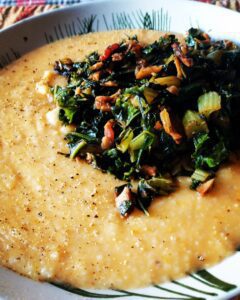 a bowl of sharp cheddar grits with sauteed green, bacon, and wild mushrooms
