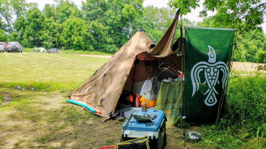 Big Agnes UL backpacking tent pitched underneath a One Tigris Northgaze Tipi tent, with Norse animist green raven flag visible in the background
