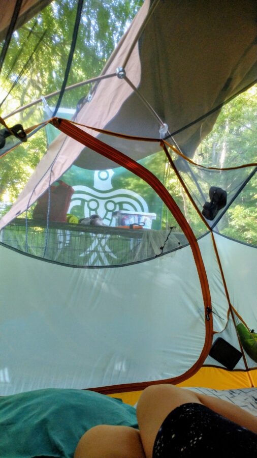 Big Agnes backpacking tent pitched underneath a One Tigris Northgaze Tipi tent, with Norse animist green raven flag visible in the background