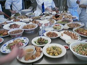 A stainless restaurant table is covered in dishes of food to be evaluated in a Kendall College Culinary school class.