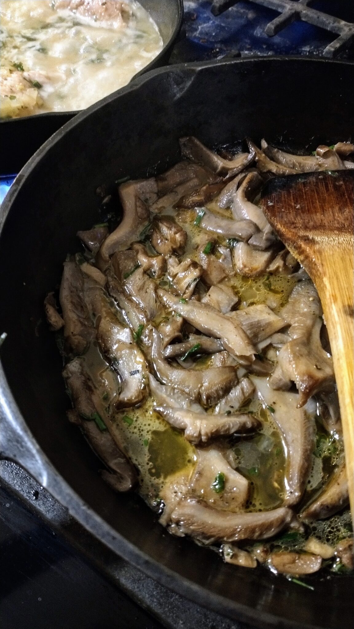 sliced wild blewit mushrooms sauteing in cream sauce in a cast iron pan.