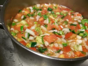 a pot of chopped tomato, onion, and pepper being cooked down into salsa to can
