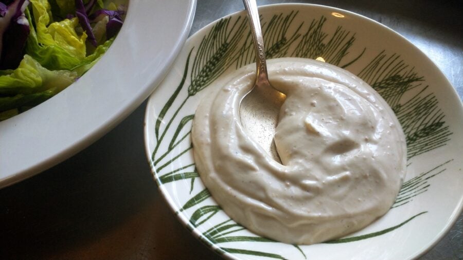 dish of creamy salad dressing next to a bowl of fresh greens
