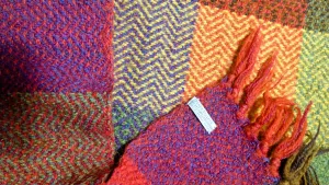 colorful handwoven blanket with herringbone pattern and a tag that reads, "Berea College Student Craft Institute, Berea Kentucky 40402"