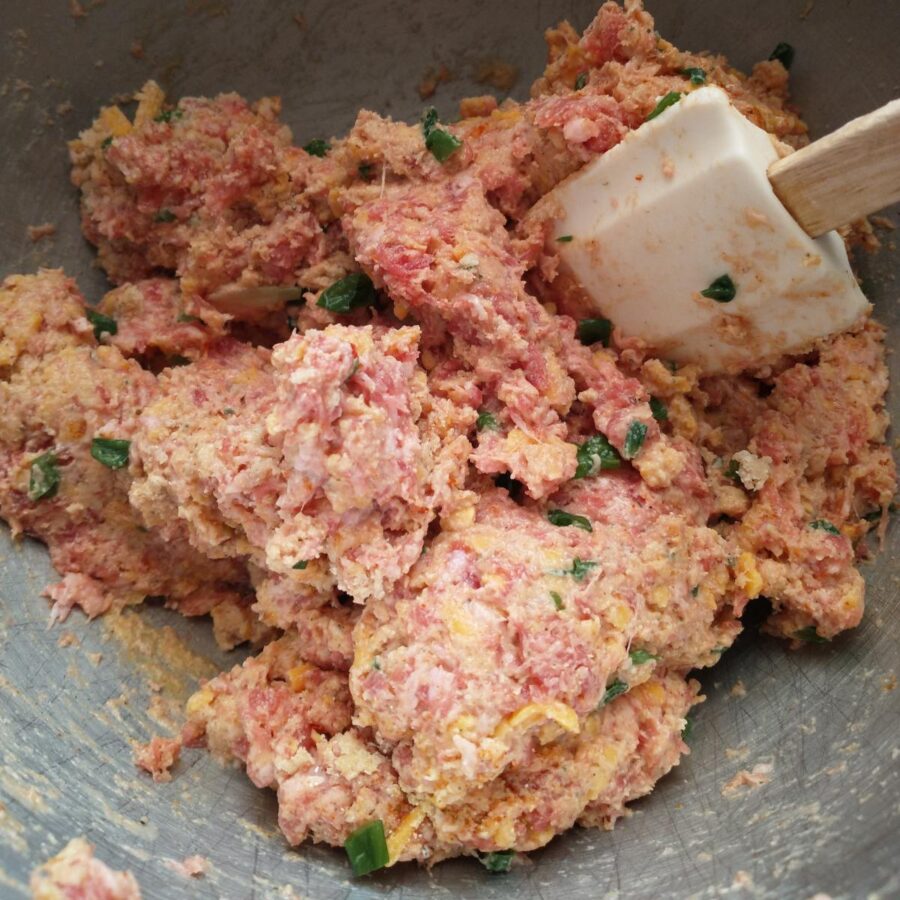 all ingredients for the southern sausage and cheese balls mixture in a bowl being stirred with a spatula.