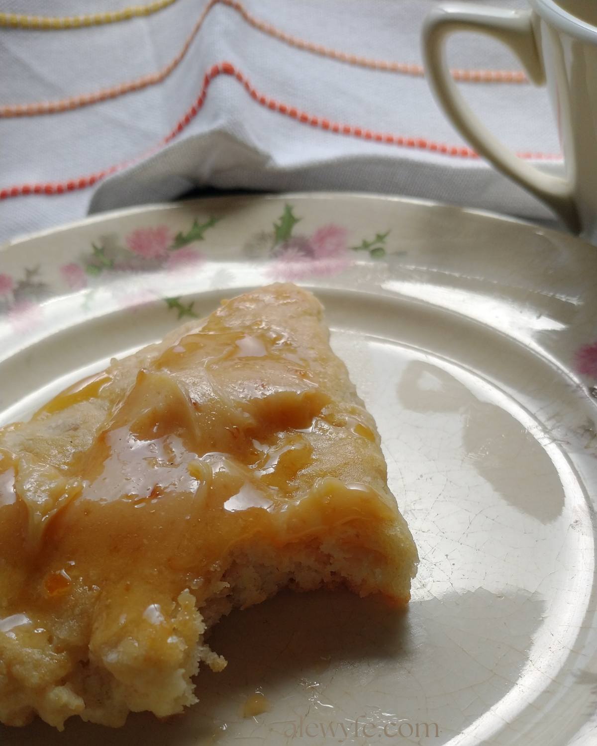 lemon oat scone topped with melting marmalade butter with a bite taken from one corner