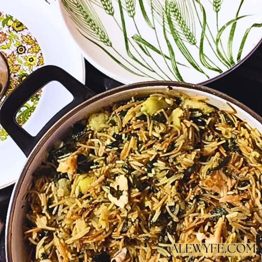 A pot of lemon vermicelli rice with artichoke hearts and sauteed greens ready to serve, next to a vintage serving bowl printed with stalks of green wheat.