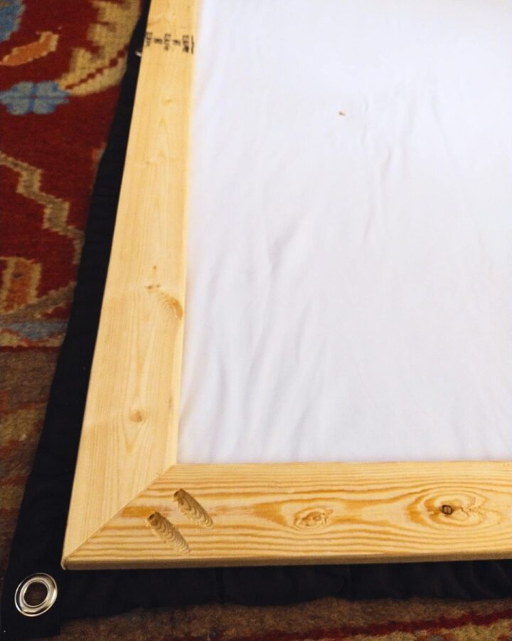corner detail photo of screen construction showing pocket holes in miter joint and lining up the projector screen to attach to frame