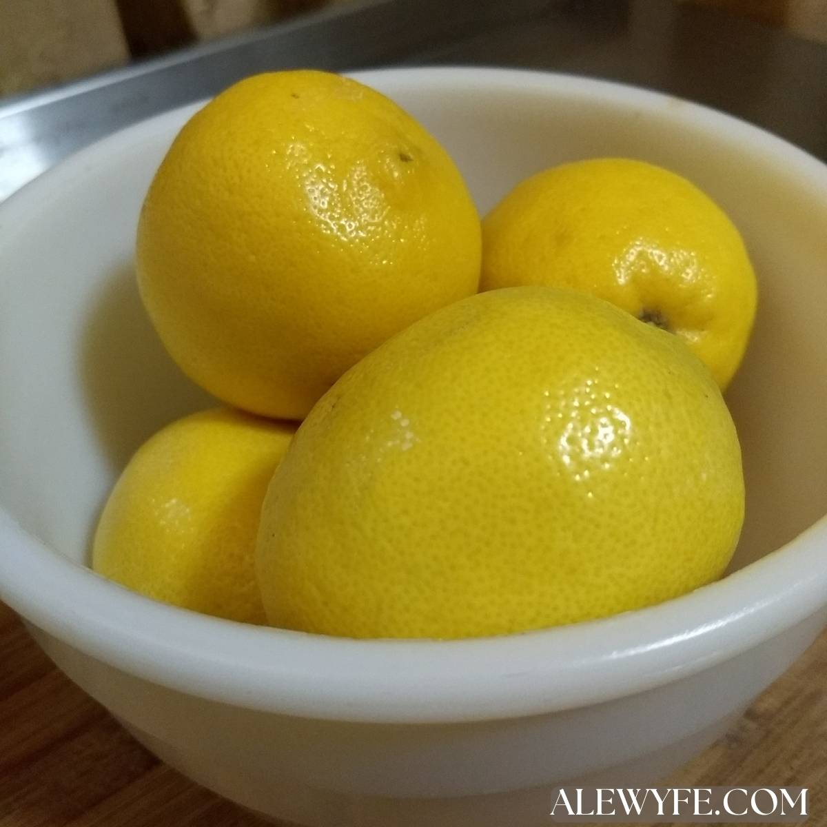 a white pyrex bowl filled with bright yellow lemons