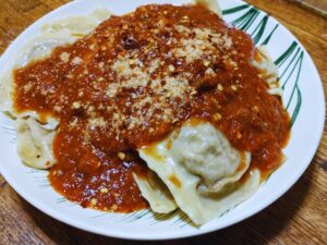 bowl of fresh homemade sausage ravioli topped with zesty tomato sauce, Parmesan, and red pepper flakes