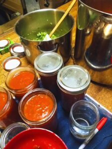 an array of canning equipment on a countertop- pots, jars, spatulas, lids, a jar funnel, and a sharpie