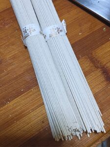 two bundles of dried buckwheat soba noodles bound with paper ribbons printed with gold characters