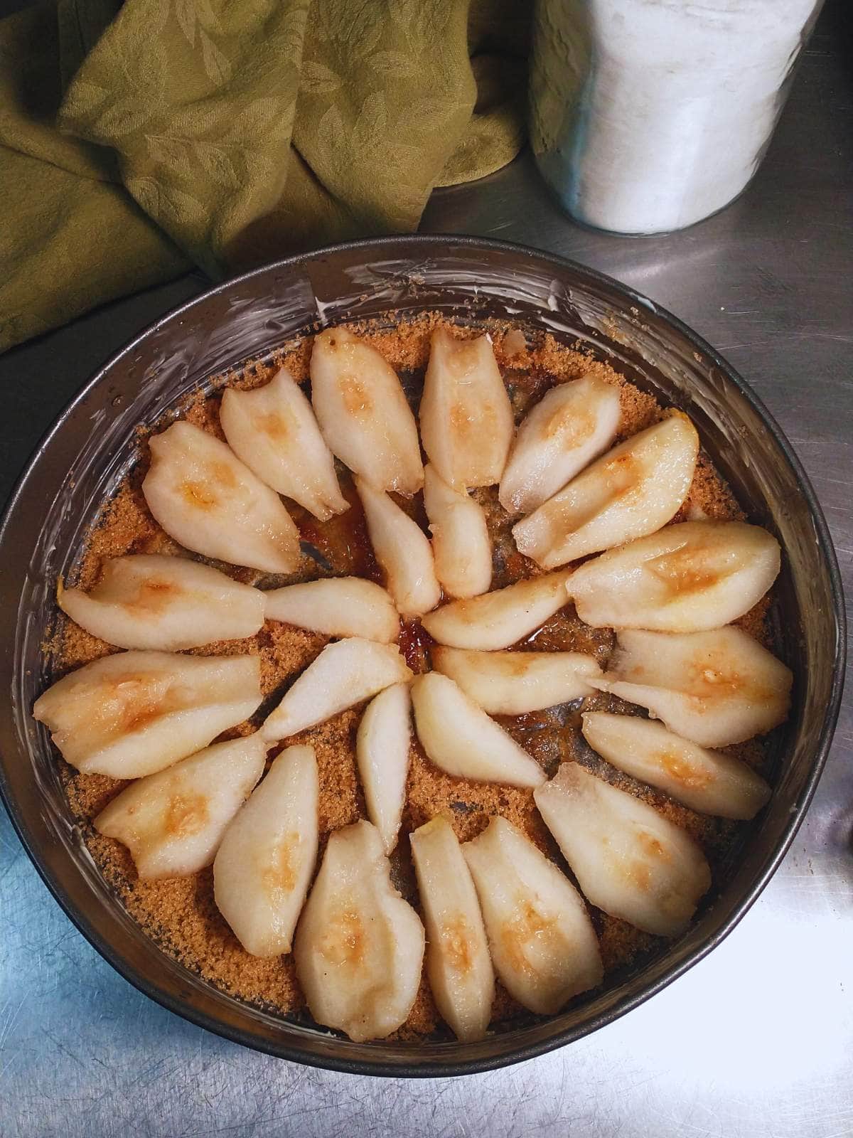 a springform baking pan lined with brown sugar and pear slices arranged on top of them
