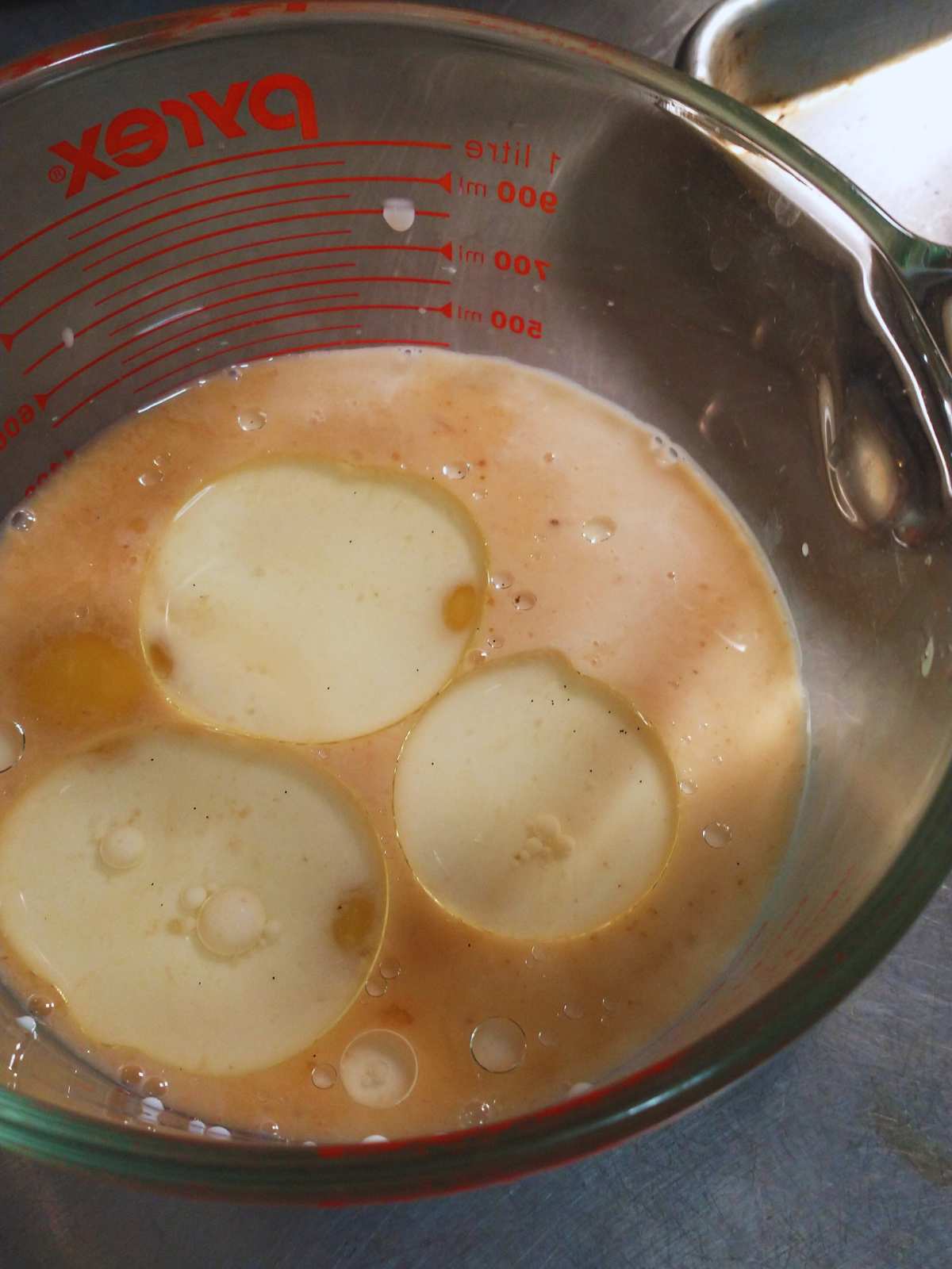 a large pyrex measuring cup with milk, eggs, vanilla, and vegetable oil ready to be whisked together for pear upside-down cake