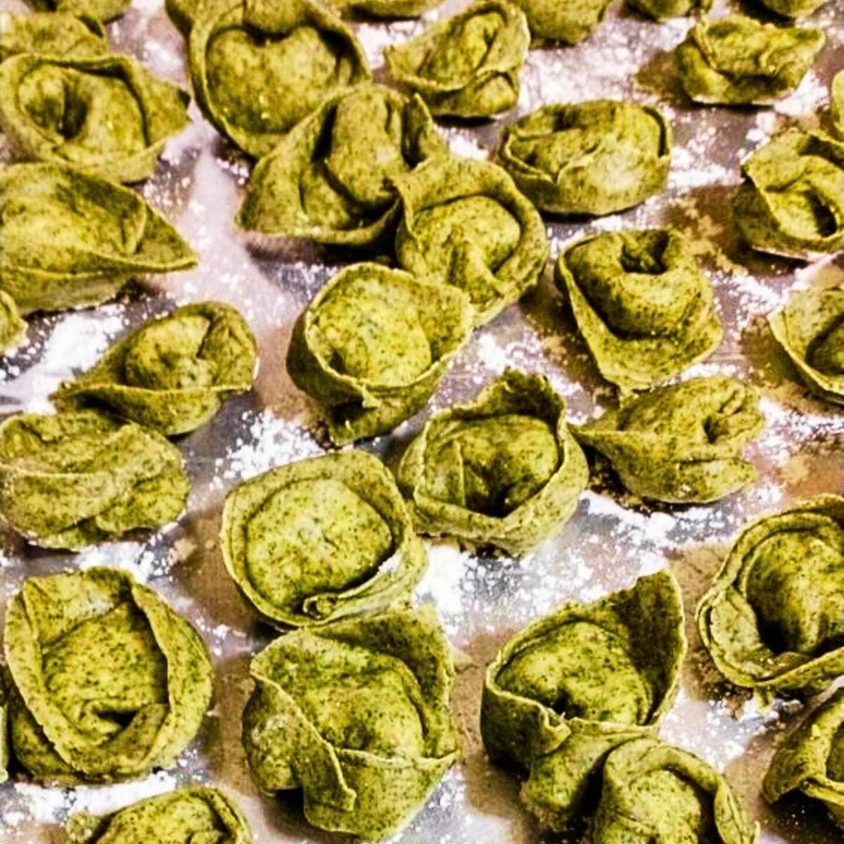 freshly-shaped parmesan artichoke tortellini on a sheet pan