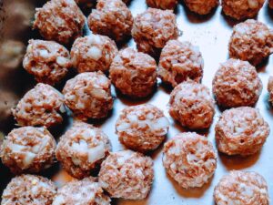 a sheet tray of shaped raw meatballs.