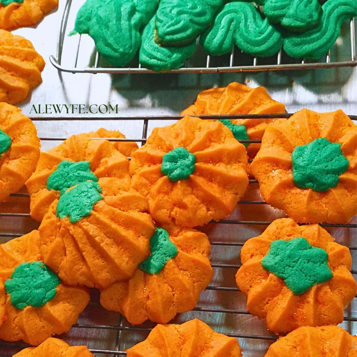 freshly baked pumpkin shaped piped spritz cookies on a cooling rack.
