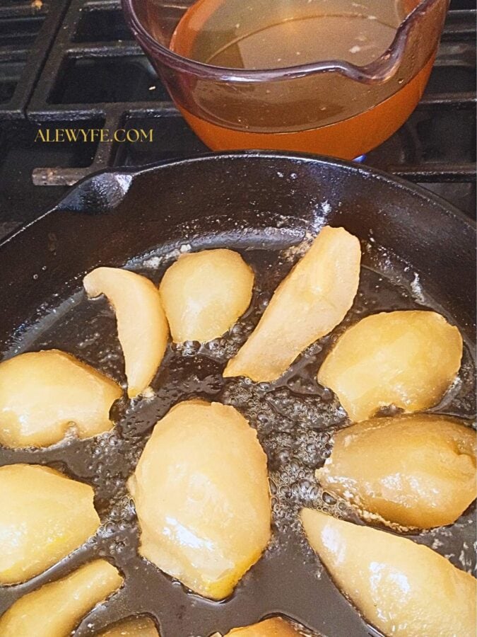 browning canned pears in butter in a cast iron pan while the buttered pear syrup reduces in the background