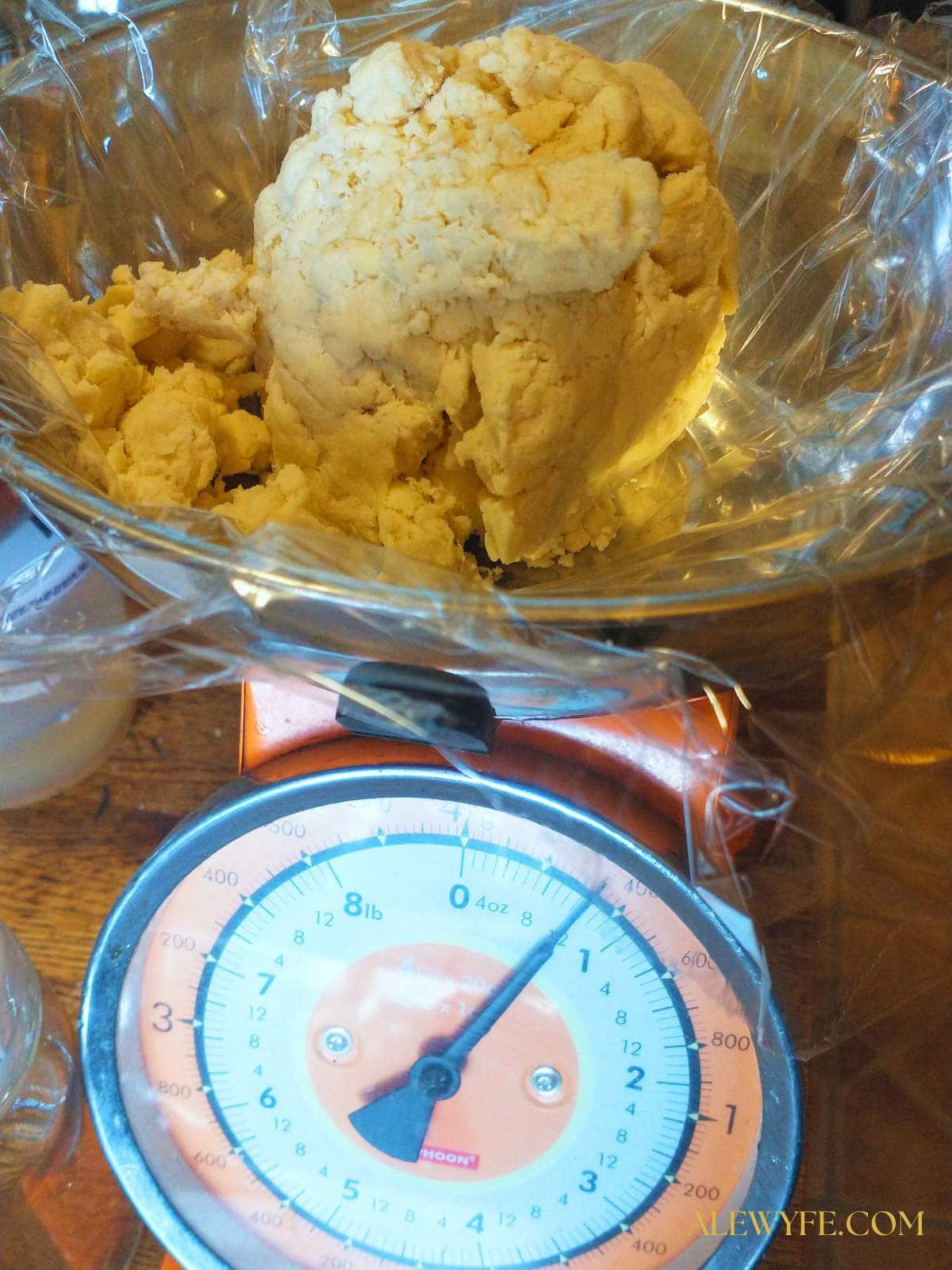 Weighing a 12 oz ball of pie dough on a bright orange kitchen scale