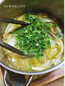 roasted tomatillo salsa ingredients in a stainless pot ready to blend into a sauce