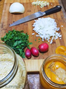 mise en place for white bean orzo, showing ingredients prepped on a cutting board next to a jar of dry orzo pasta and a jar of preserved meyer lemons