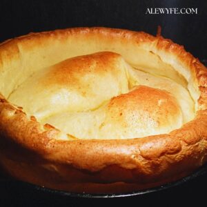 a puffy golden brown classic Yorkshire pudding against a black background