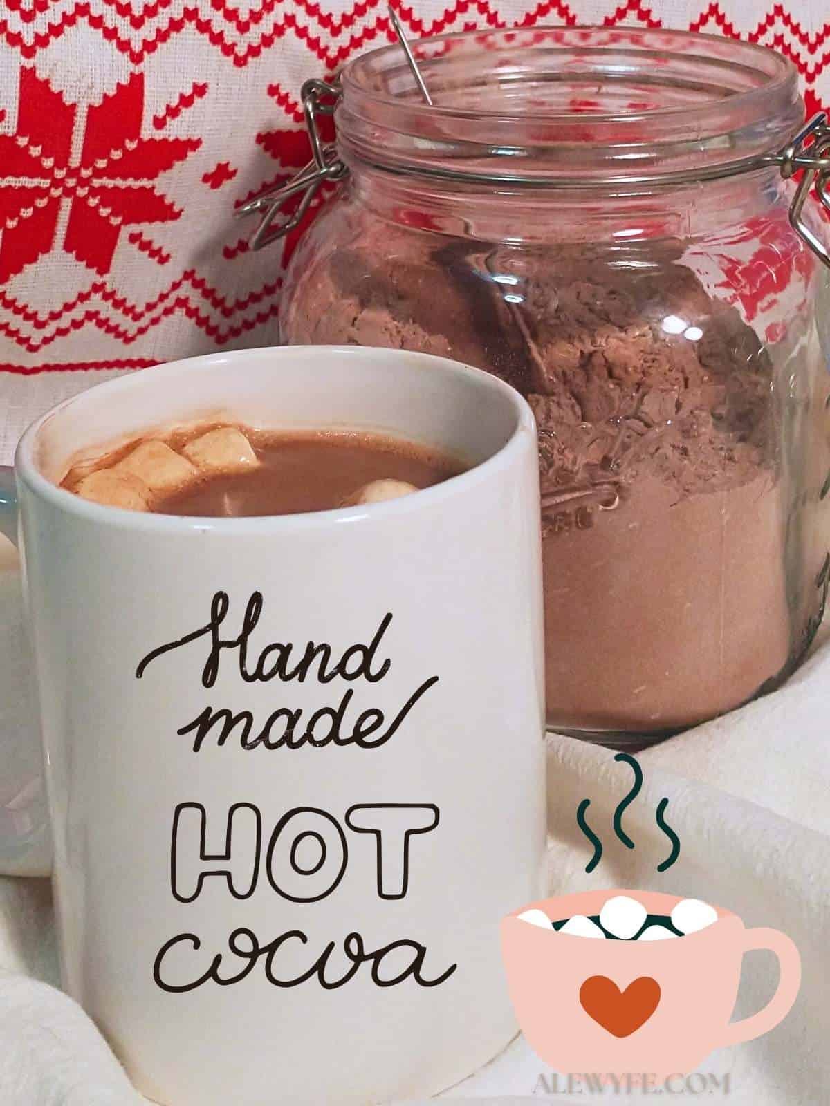 a mug of hot chocolate with marshmallows in front of a jar of hot cocoa mix. Text graphic reads, "handmade hot cocoa" in script letters  with a cartoon mug with a heart drawing