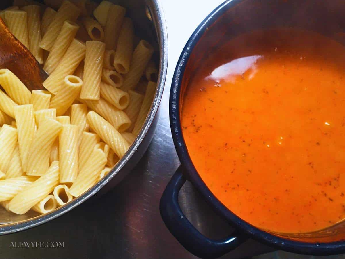 a pot of cooked rigatoni next to a pot of roasted pepper cream sauce