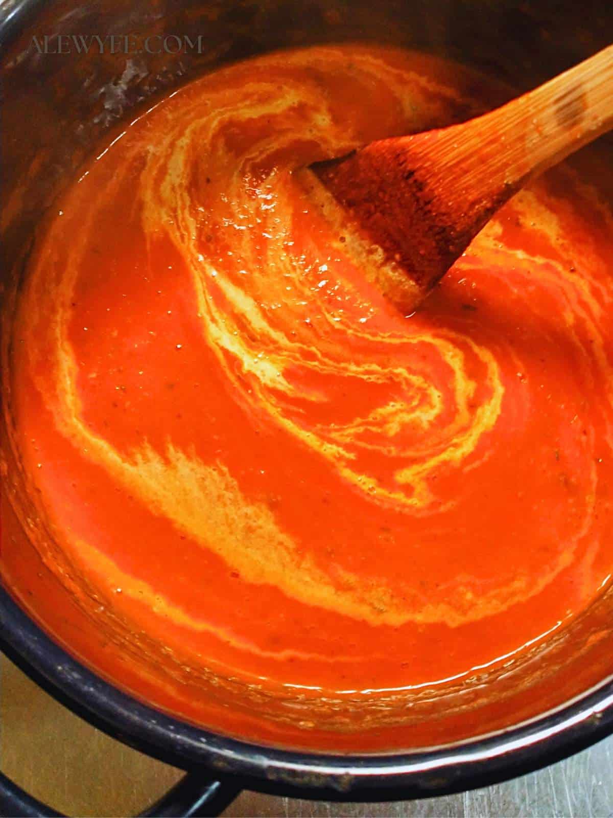 stirring a swirl of heavy cream into the roasted red pepper sauce