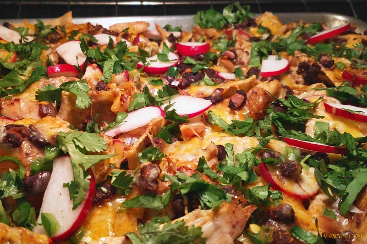 sheet pan nachos freshly baked and garnished with beans, meat, and vegetables