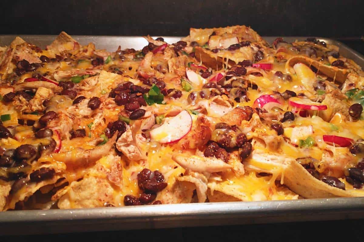 nachos baking on a sheet pan in the oven