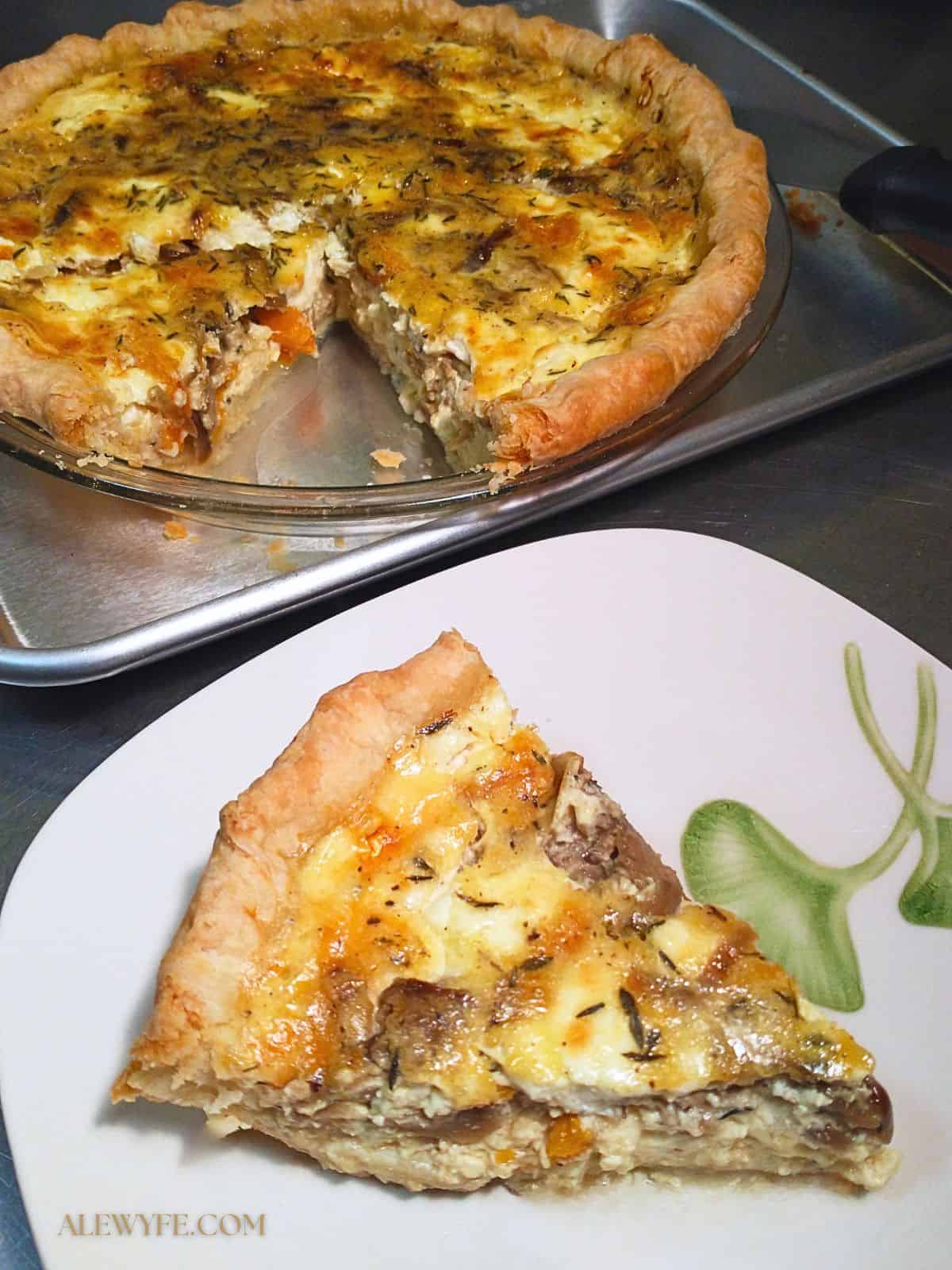 a slice of butternut squash goat cheese quiche on a plate, in front of the quiche with one slice removed.