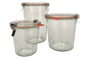 a trio of three German Weck canning jars with orange rubber seals and metal clips.