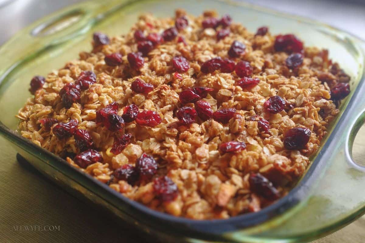 side view of apple cranberry walnut baked oatmeal baked in a green glass pyrex baking dish.