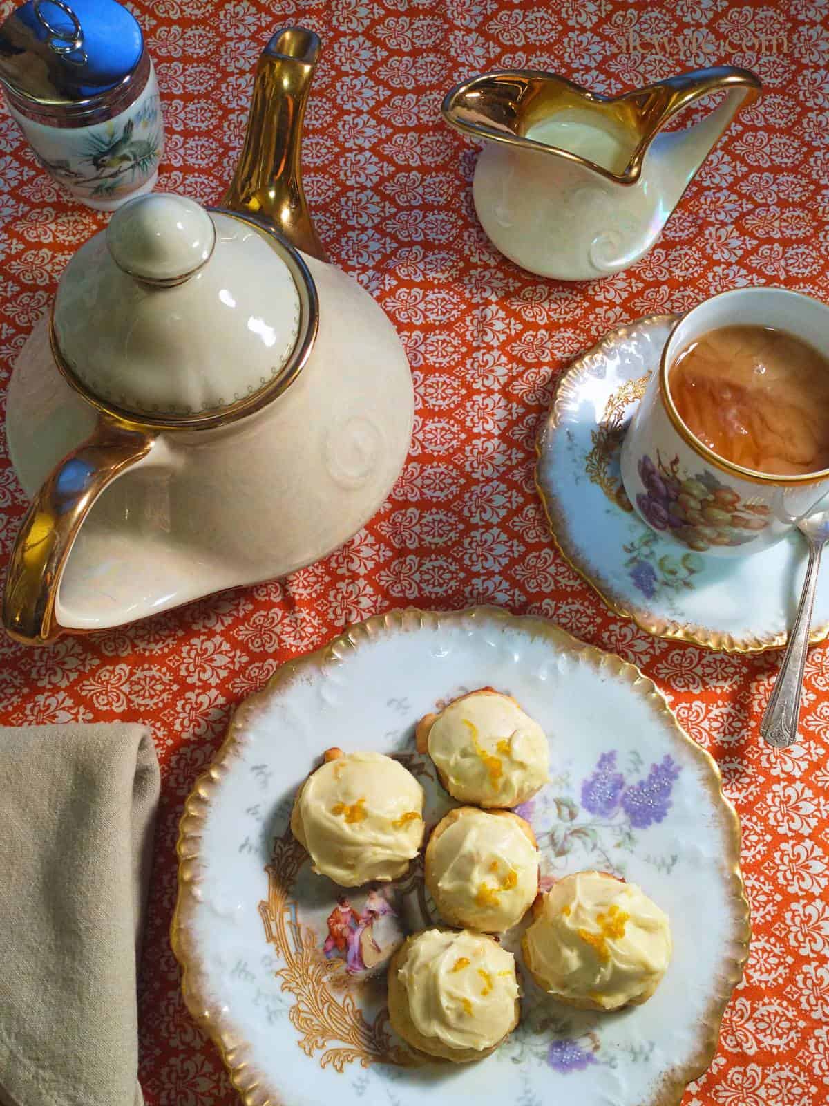 a still life with a plate of creamsicle cookies and an elegant tea setting with antique gilded handpainted Limoges china, a tea pot, and creamer.