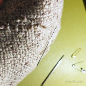 close up photo of darning repair of loose woolen weave vintage fabric.