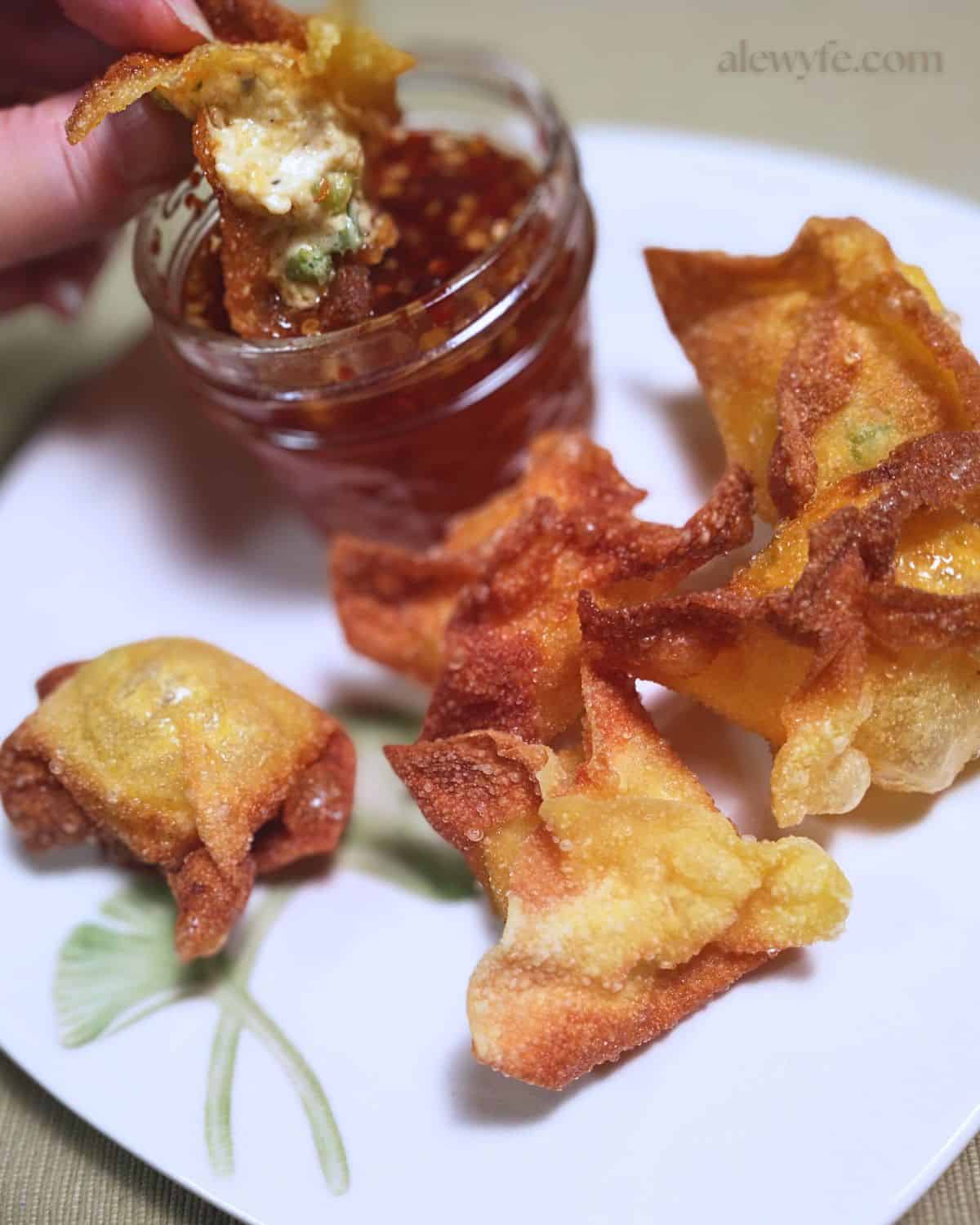 dipping a jalapeno popper wonton into sweet chili garlic sauce.
