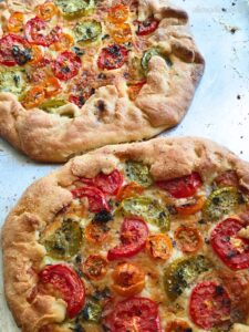 two baked heirloom tomato tarts with colorful tomatoes and cheese.