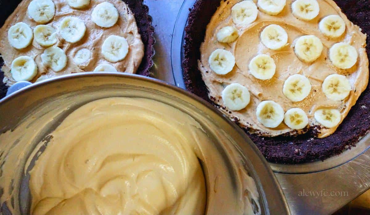 two frozen peanut butter pies, with banana slices in the middle, and a bowl of the peanut butter whipped cream layer ready to top the icebox pies.