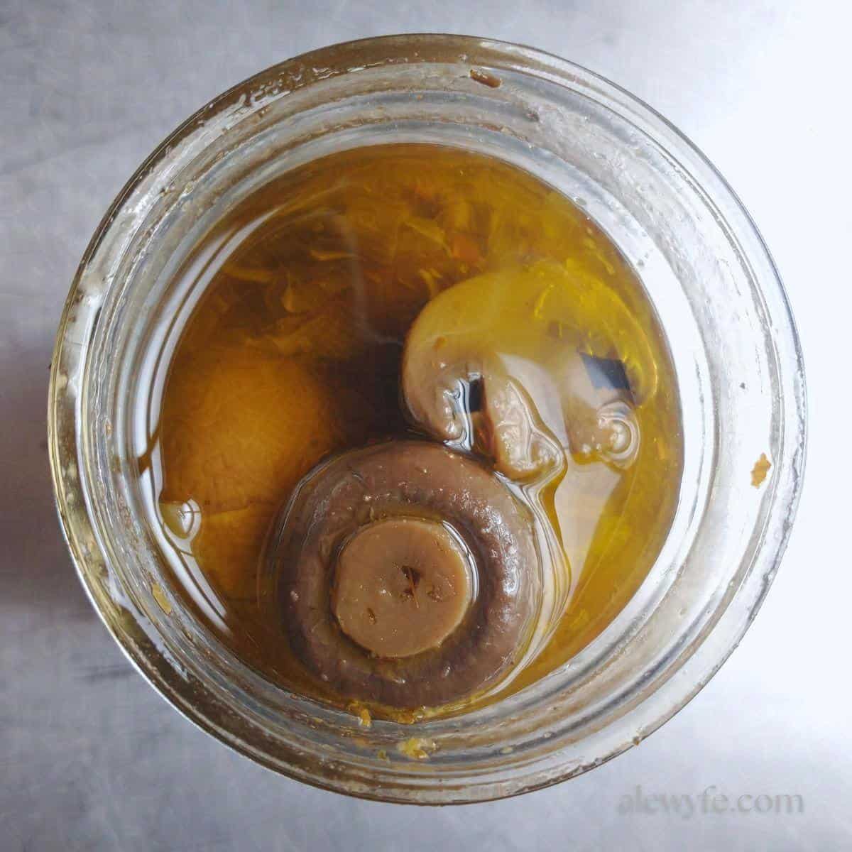 top down view of a jar of canned marinated mushrooms.