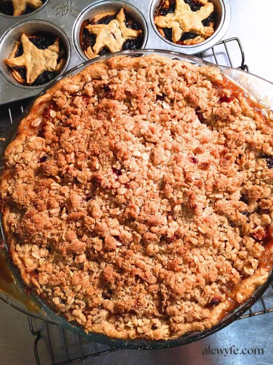 top view of a cranberry apple crumble pie next to mini mincemeat pies in a muffin tin.